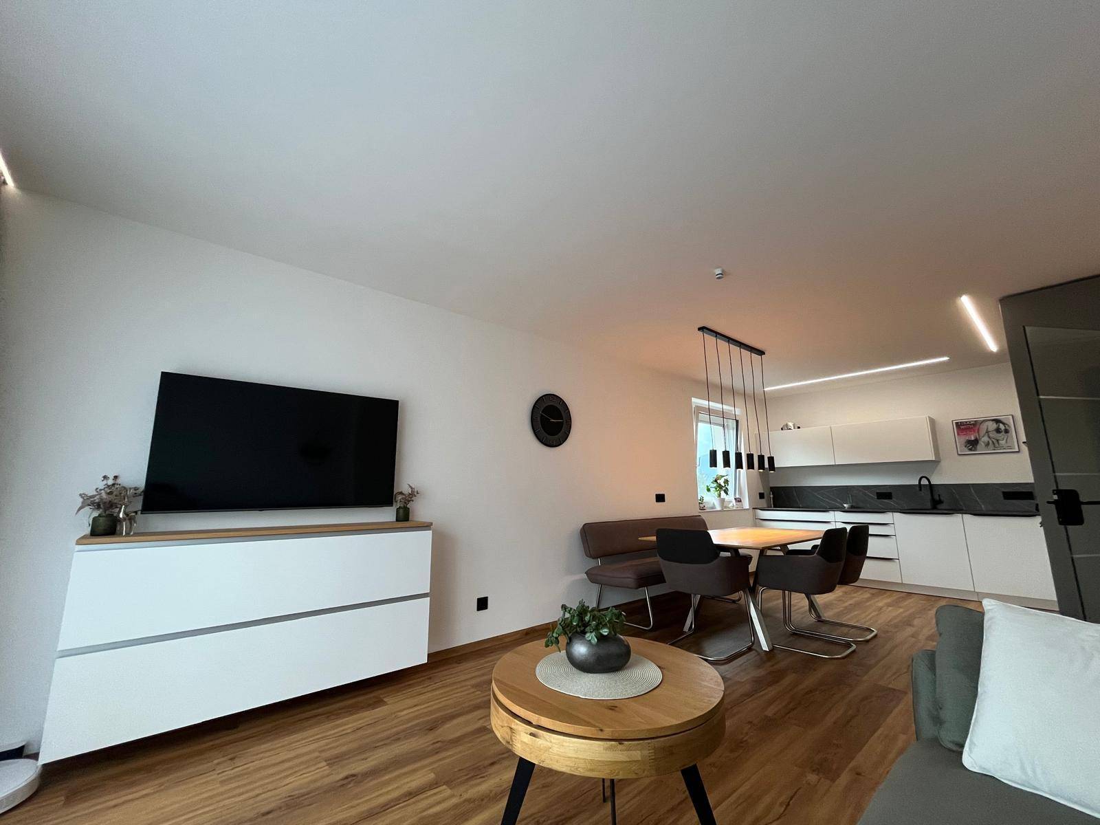 Heller Wohnbereich mit Sofa und Couchtisch, offen zur modernen Küche und Essbereich.