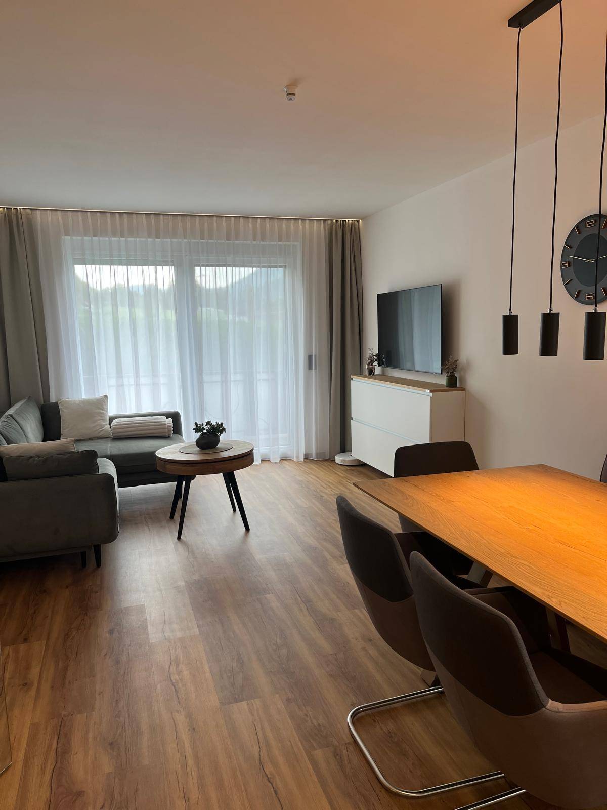 Offener Wohn- und Essbereich mit Holzboden, Esstisch und Sofa, hell und modern eingerichtet.