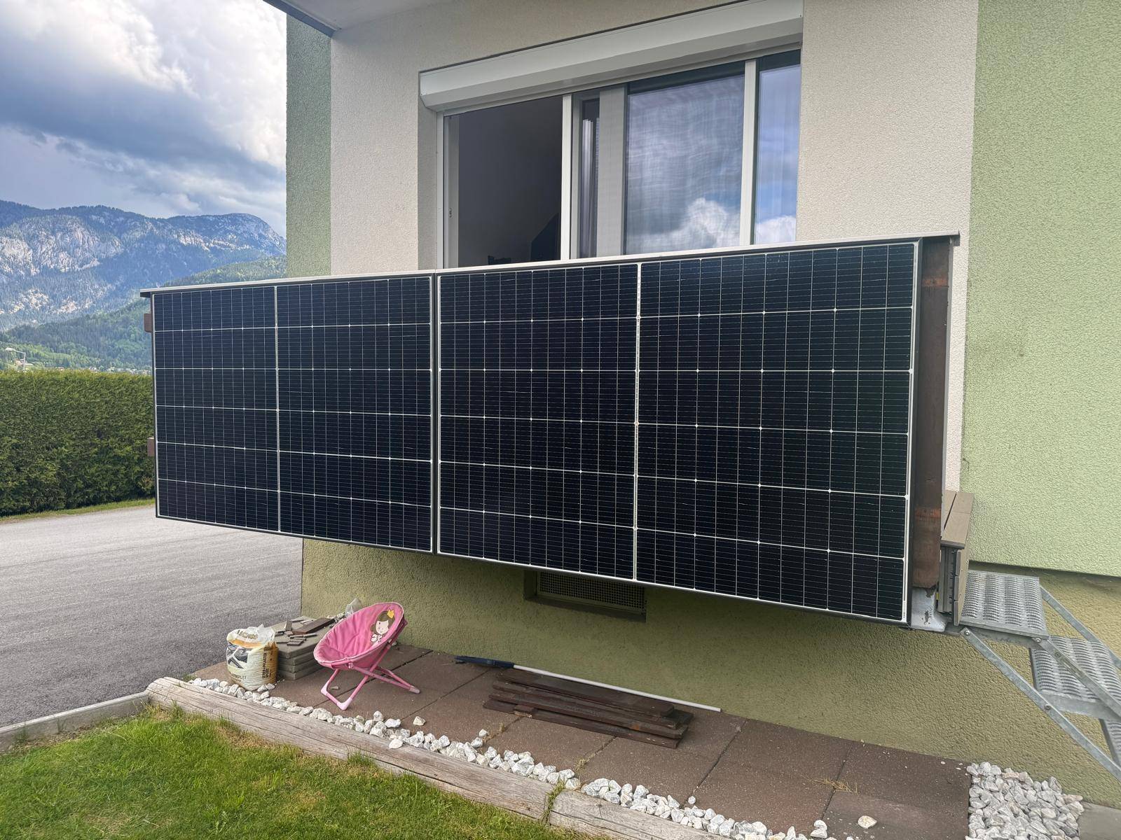 Balkon mit Solarmodulen und Blick auf die Berge und grüne Umgebung.