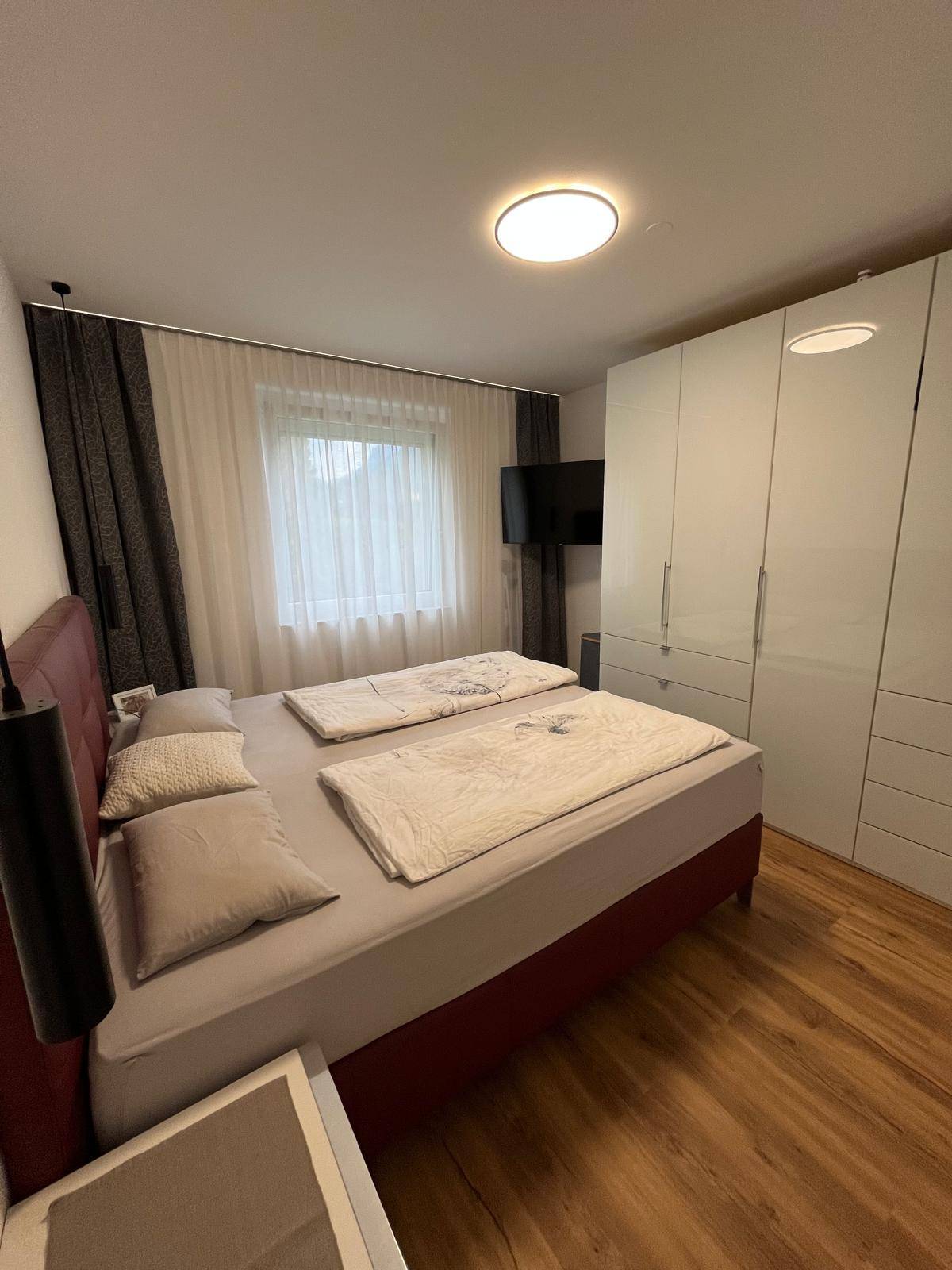 Geräumiges Schlafzimmer mit Doppelbett, weißem Kleiderschrank und Laminatboden.