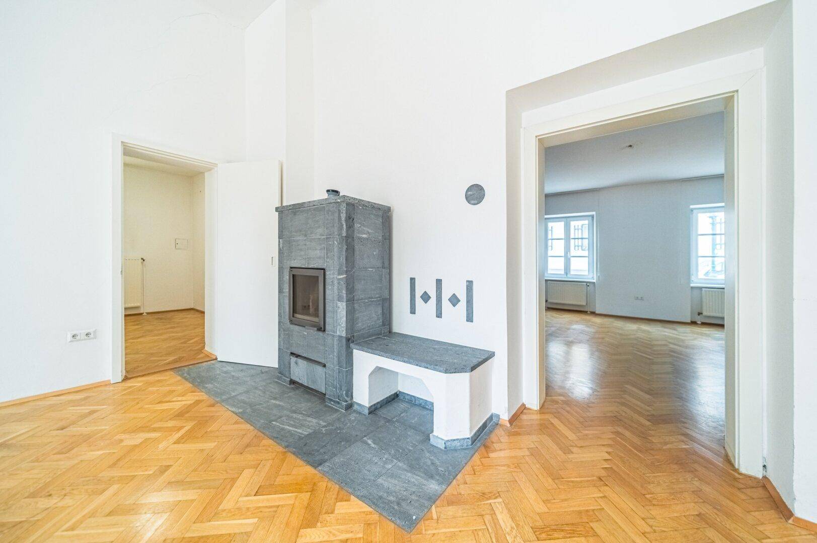 Moderner Kaminofen mit Sitzbank in einem hellen Wohnzimmer mit Fischgrätparkett.