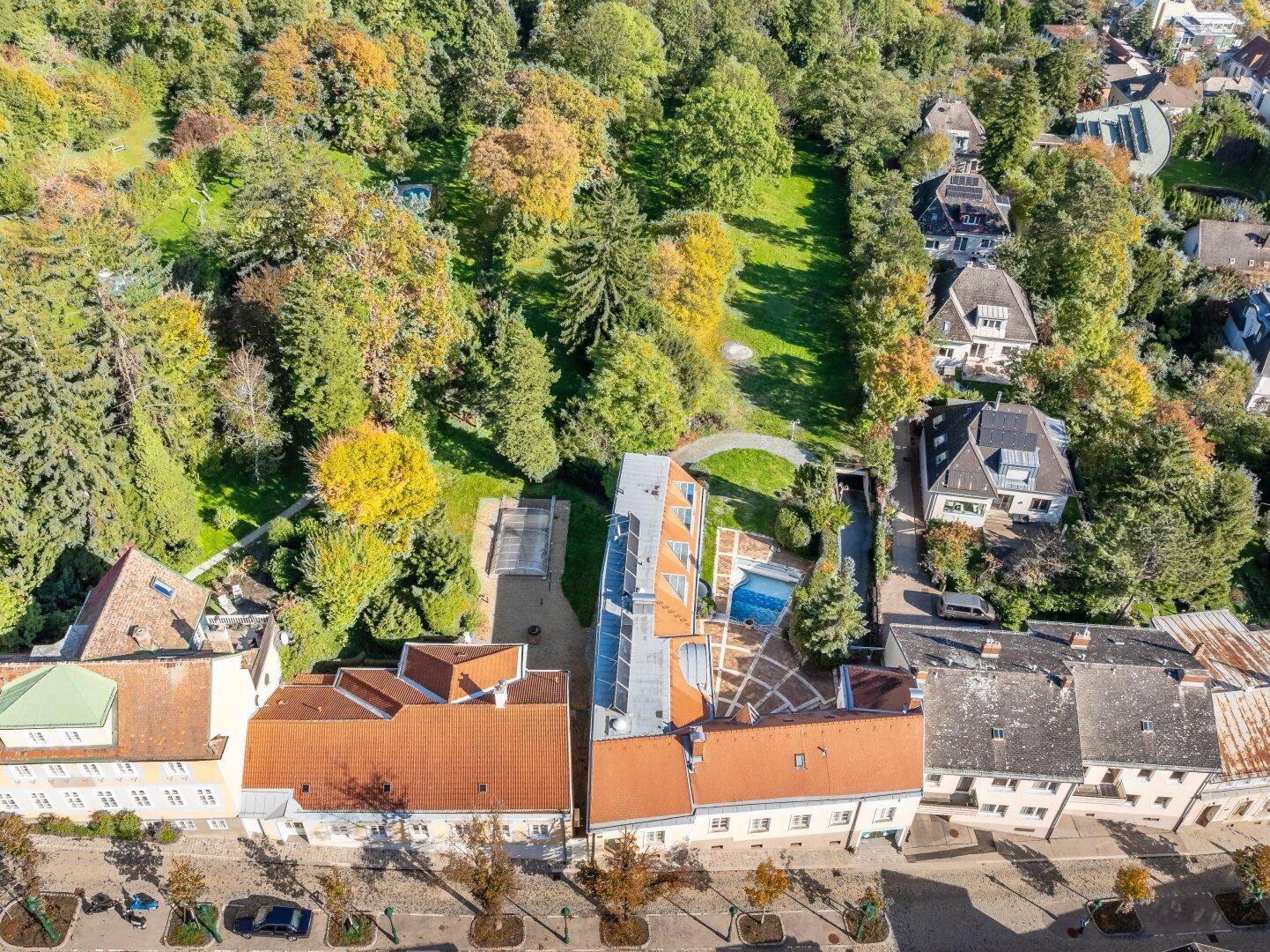 Luftaufnahme des Anwesens mit großem Garten, Pool und umliegender Wohnbebauung.
