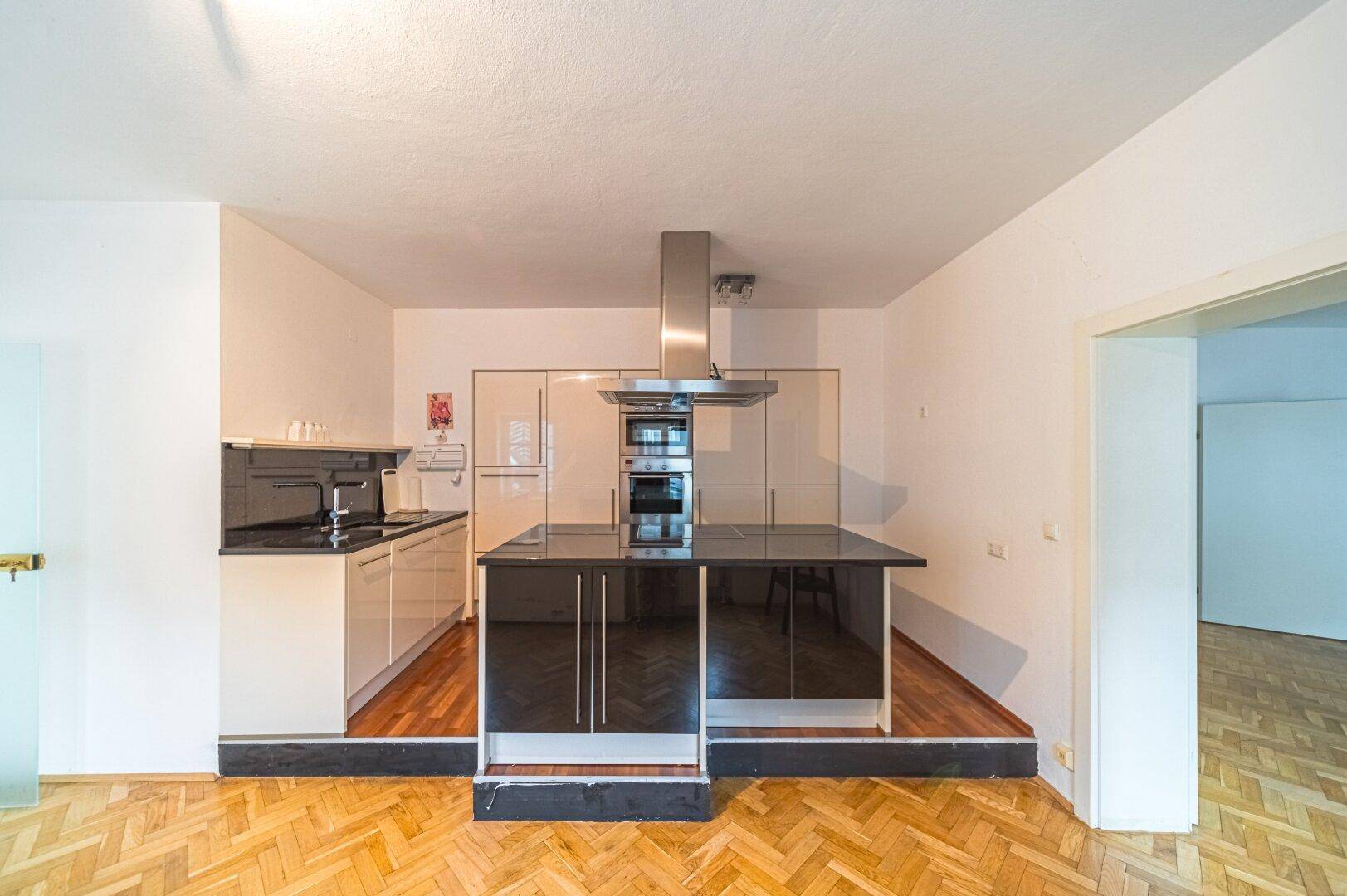 Moderne Küche mit Kochinsel, integrierten Geräten und glänzenden Oberflächen.