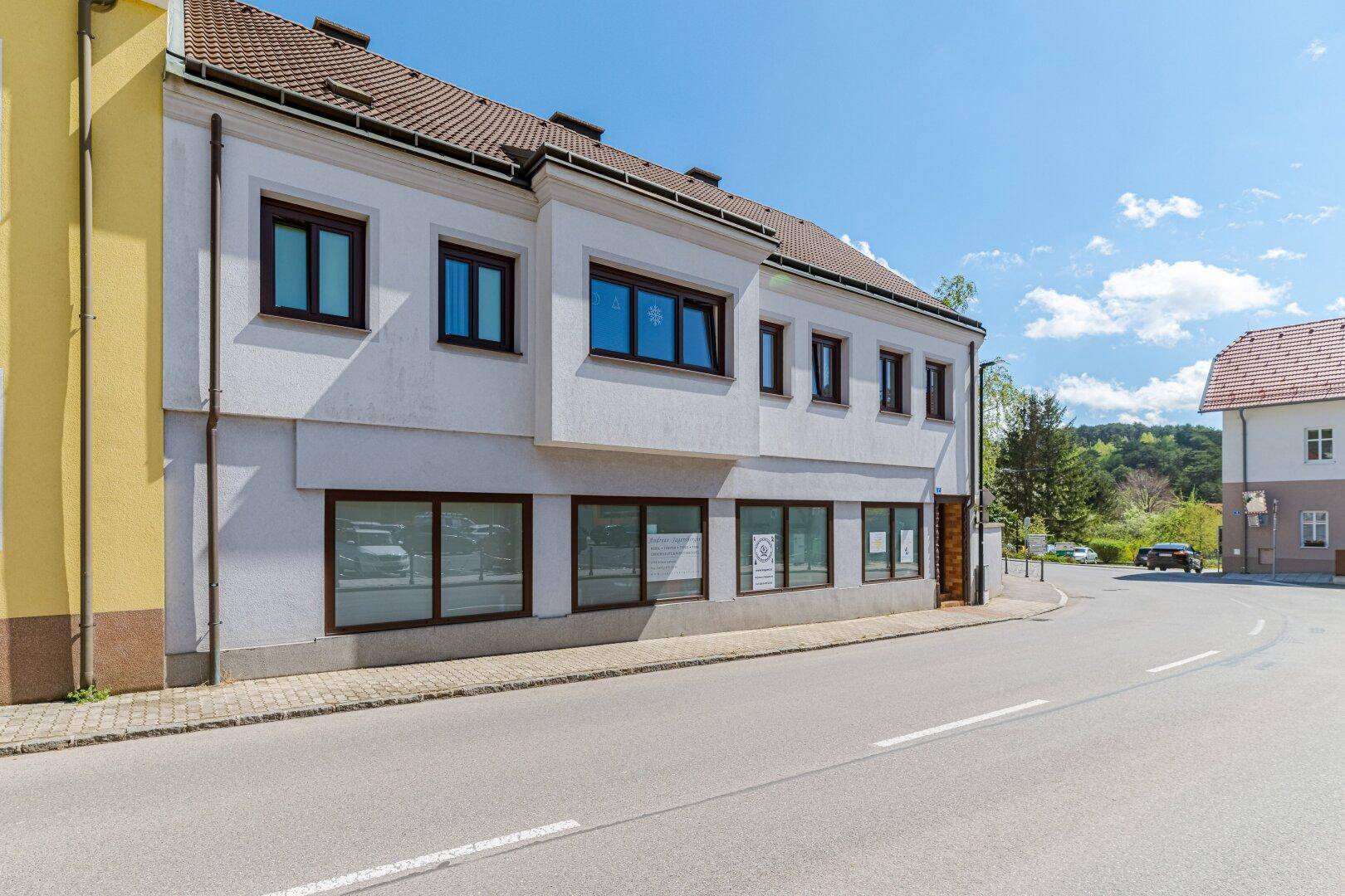 Seitenansicht des Gebäudes von der Straße aus mit großen Fenstern im Erdgeschoss.