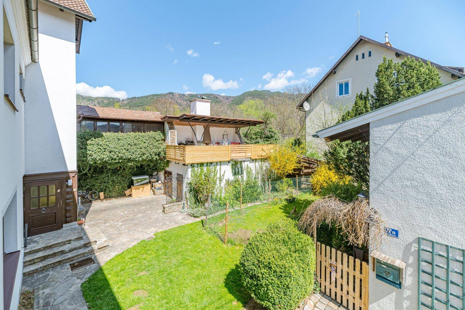 Gepflegter Gartenbereich mit Rasenfläche und einer erhöhten Terrasse im Hintergrund.