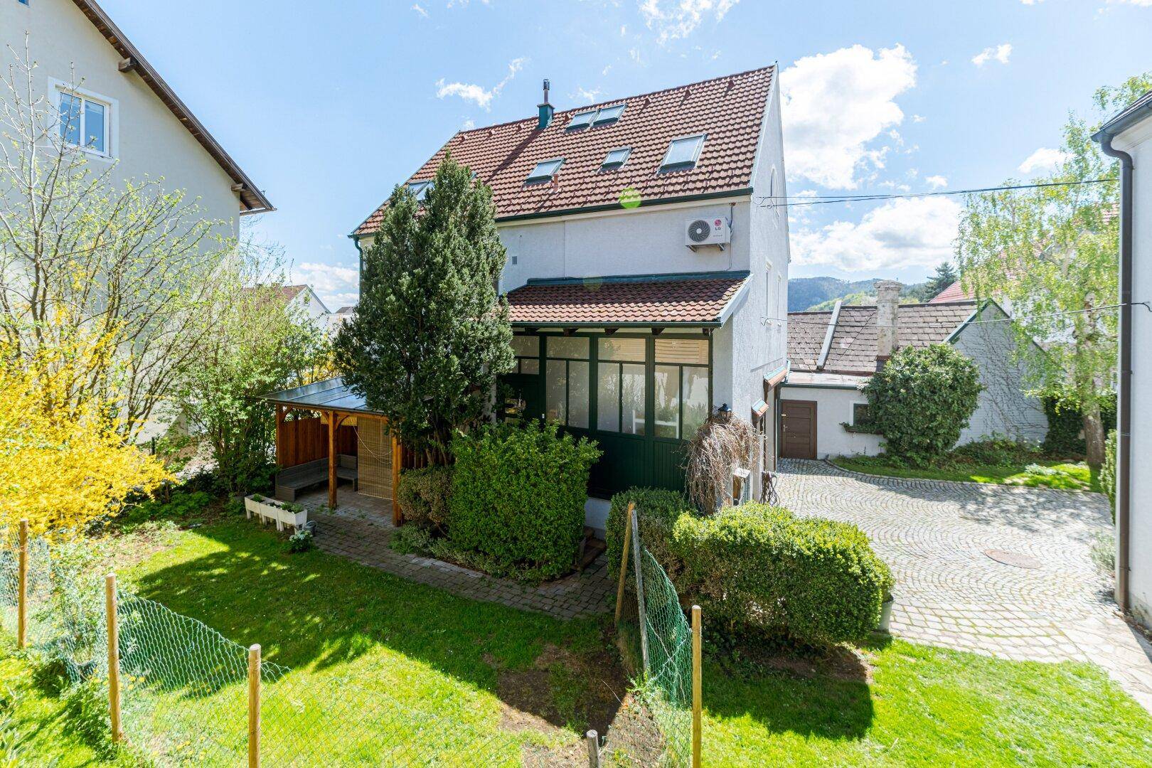 Hinterhof mit Rasenfläche, überdachtem Sitzbereich und Blick auf das Hauptgebäude.