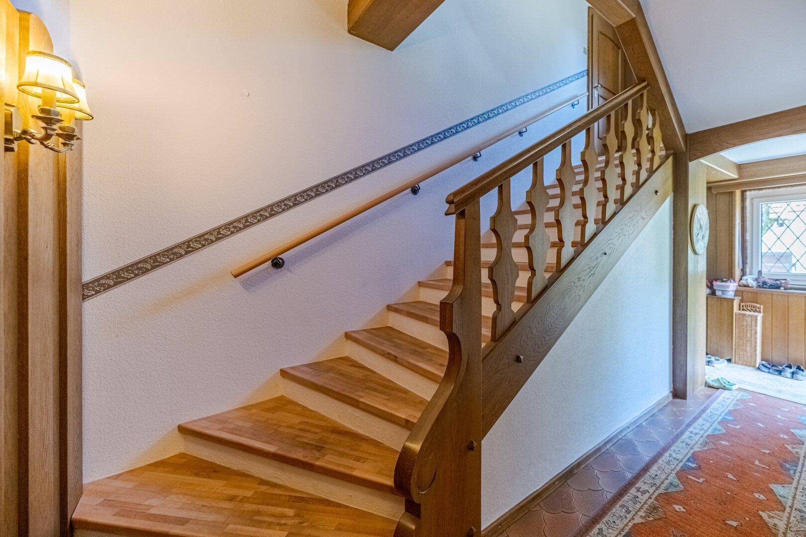 Heller Treppenaufgang mit Holzstufen und Geländer, der zu den oberen Etagen führt.