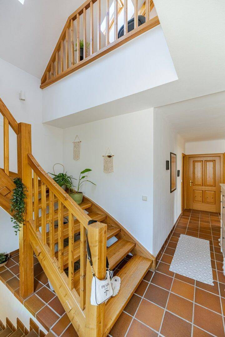 Geräumiger Flur mit Holztreppe, Terrakotta-Fliesen und Zugang zu weiteren Räumen.