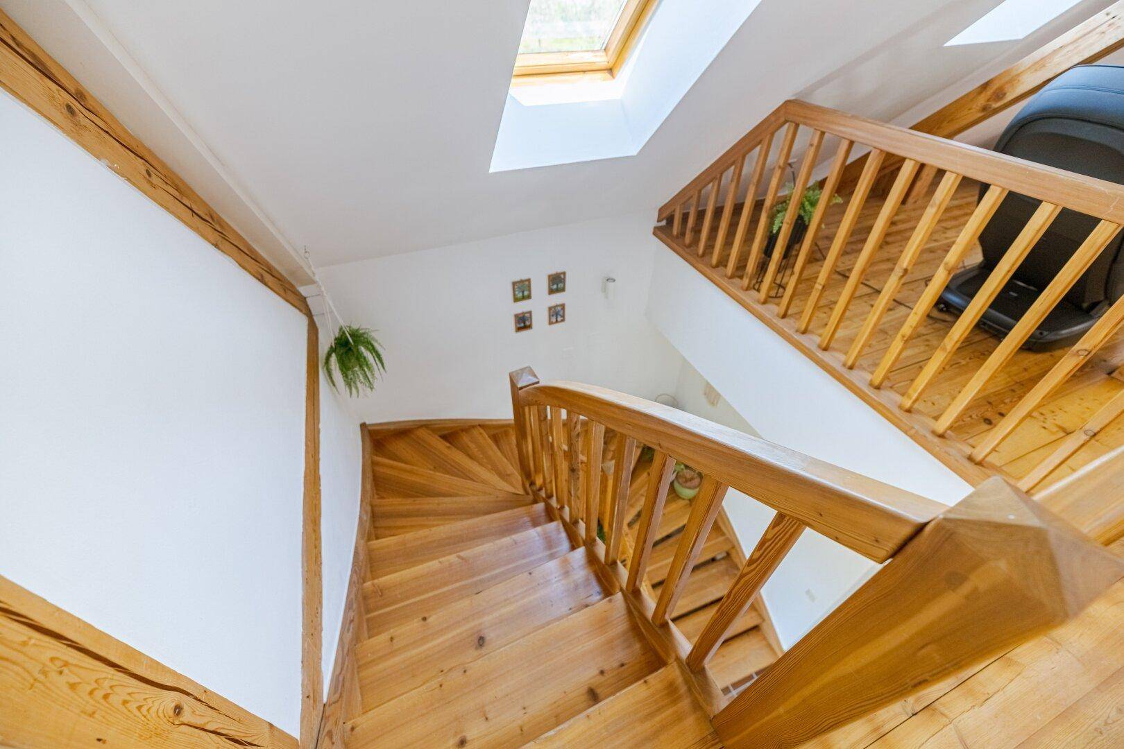 Holztreppe führt vom Dachgeschoss nach unten, mit viel natürlichem Licht von oben.
