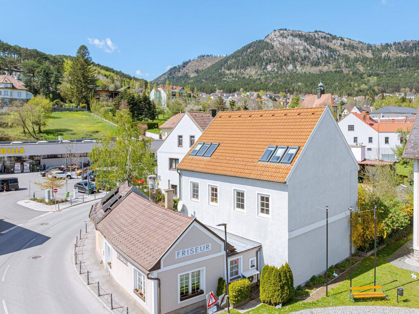 Luftaufnahme der Ortschaft mit dem Anwesen, umliegenden Gebäuden und Bergpanorama.