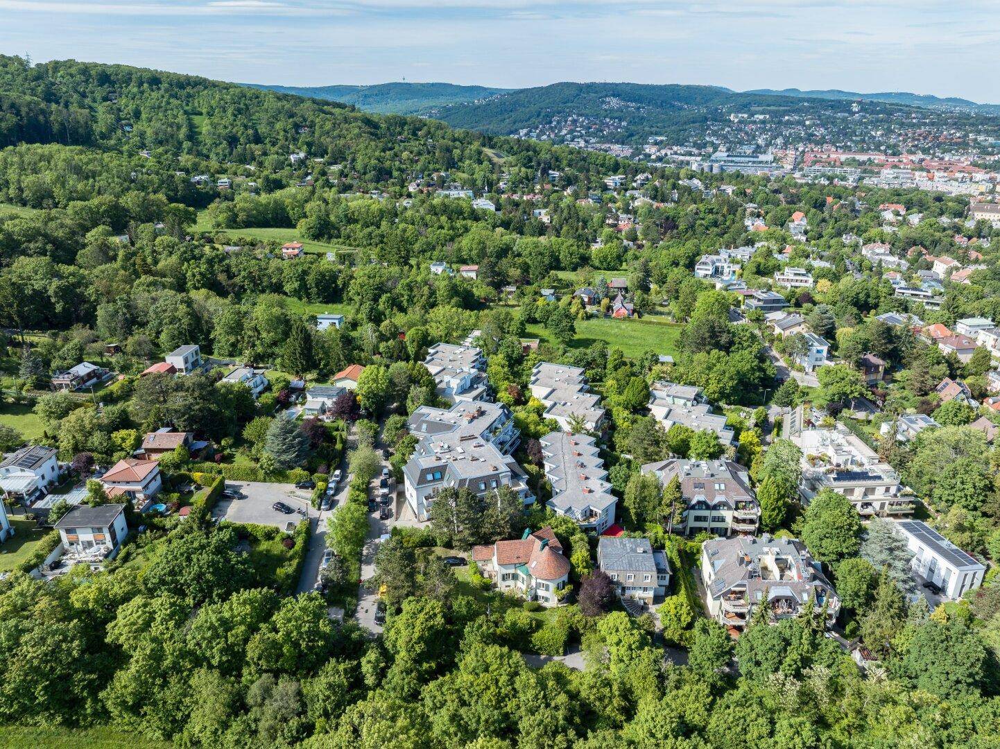 Panoramablick auf die grüne Wohngegend mit vielen Häusern und bewaldeten Hügeln.