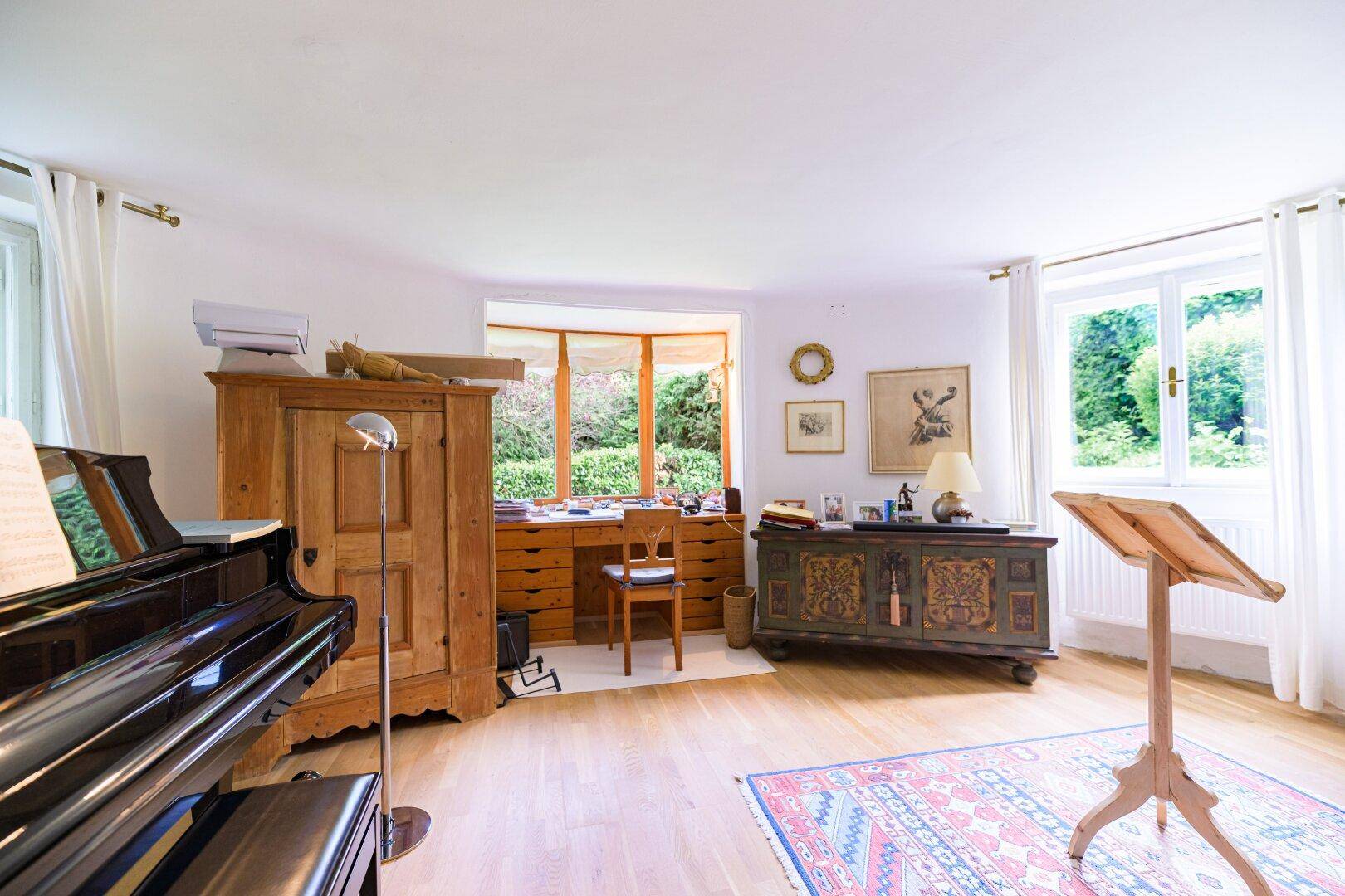 Geräumiges Arbeitszimmer mit Holzboden, großem Schreibtisch und Blick in den Garten.