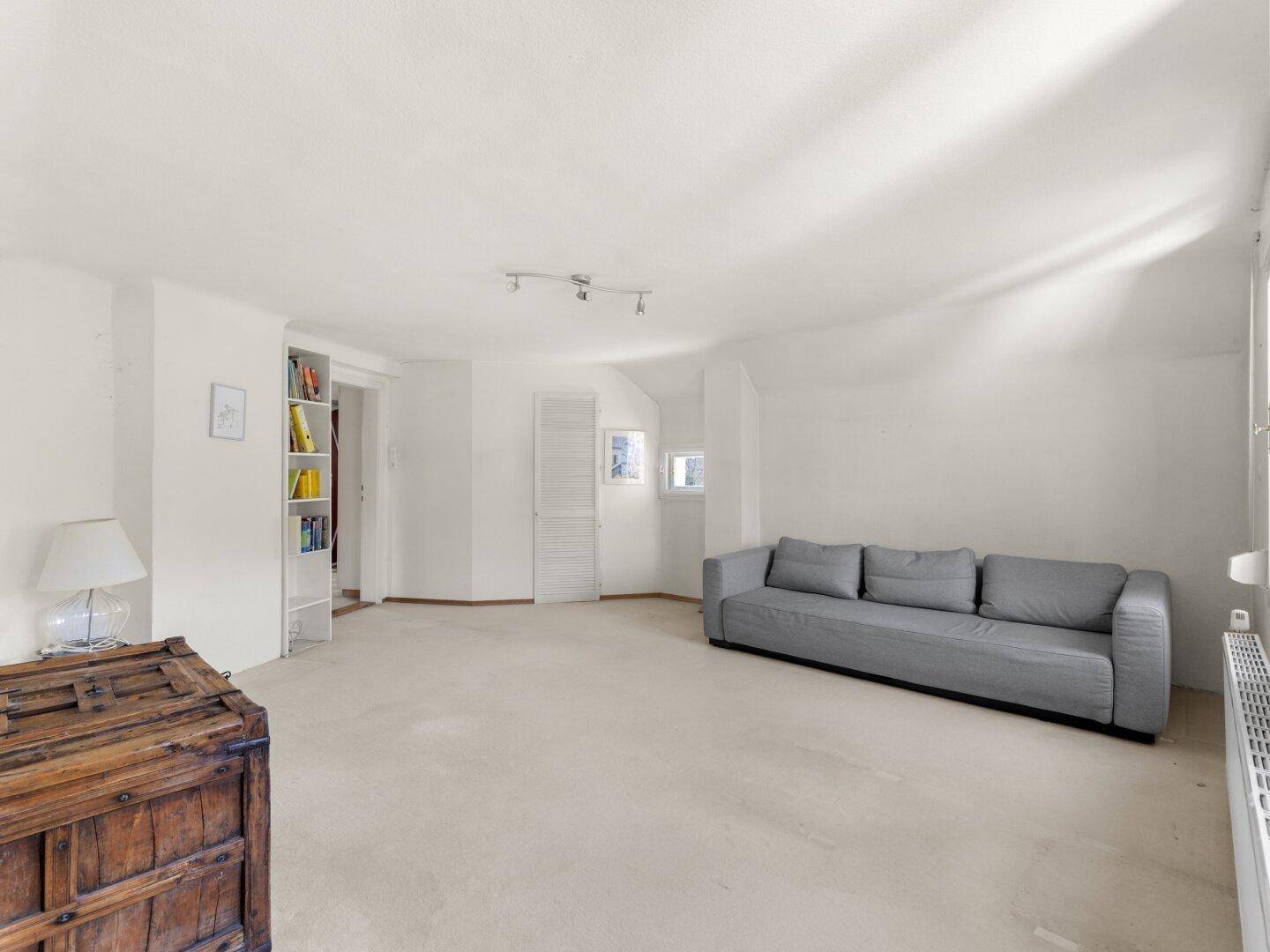 Heller Wohnraum mit Teppichboden, modernem Sofa und integrierten Regalen.