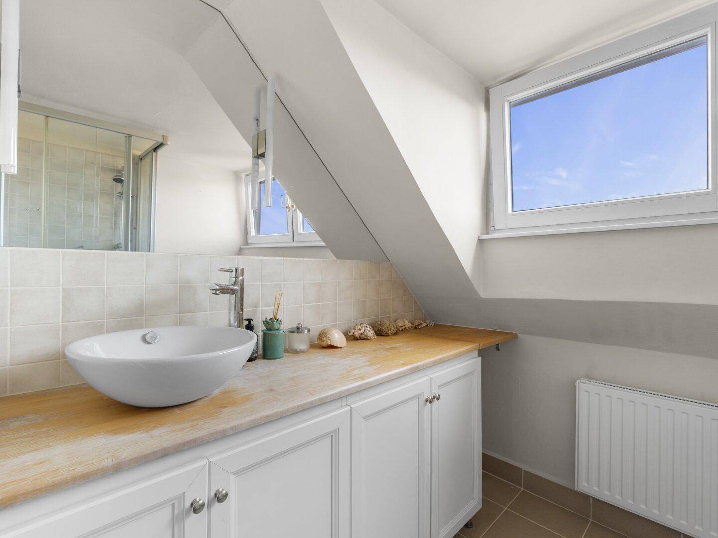 Modernes Badezimmer im Dachgeschoss mit Waschtisch, Fenster und Schrägdach.