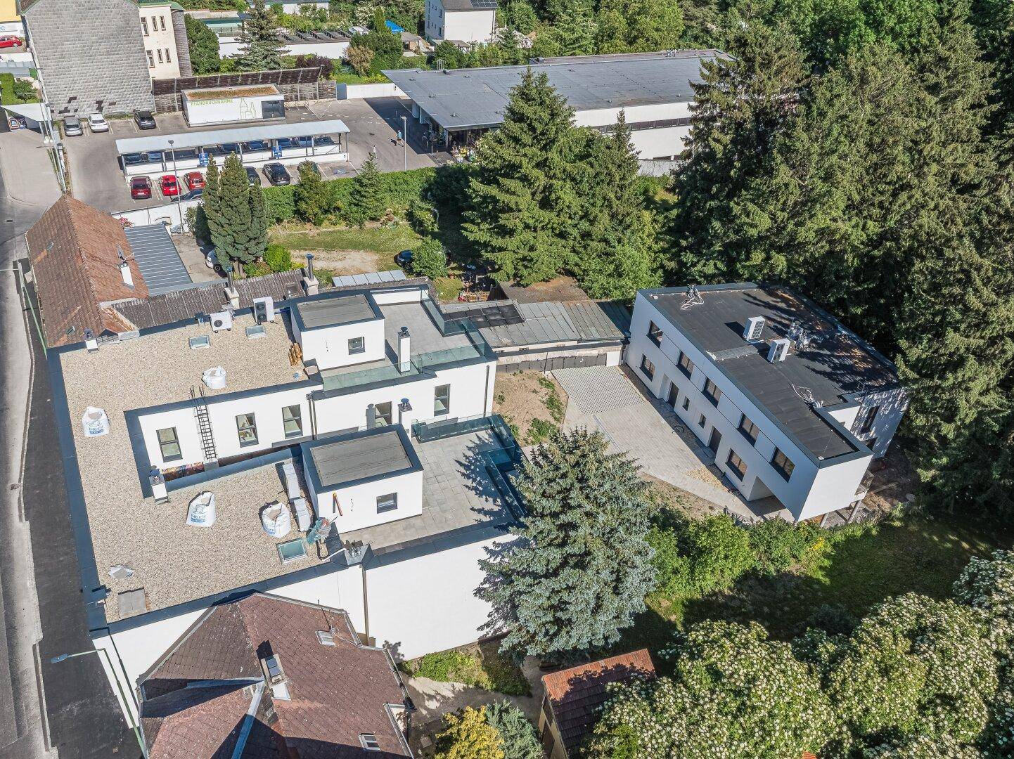 Detaillierte Luftaufnahme der Flachdachgebäude und der umliegenden grünen Landschaft.