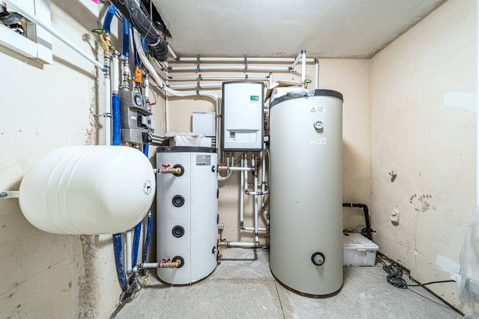 Technikraum mit modernen Heizungsanlagen und Warmwasserspeichern in einem Neubau.