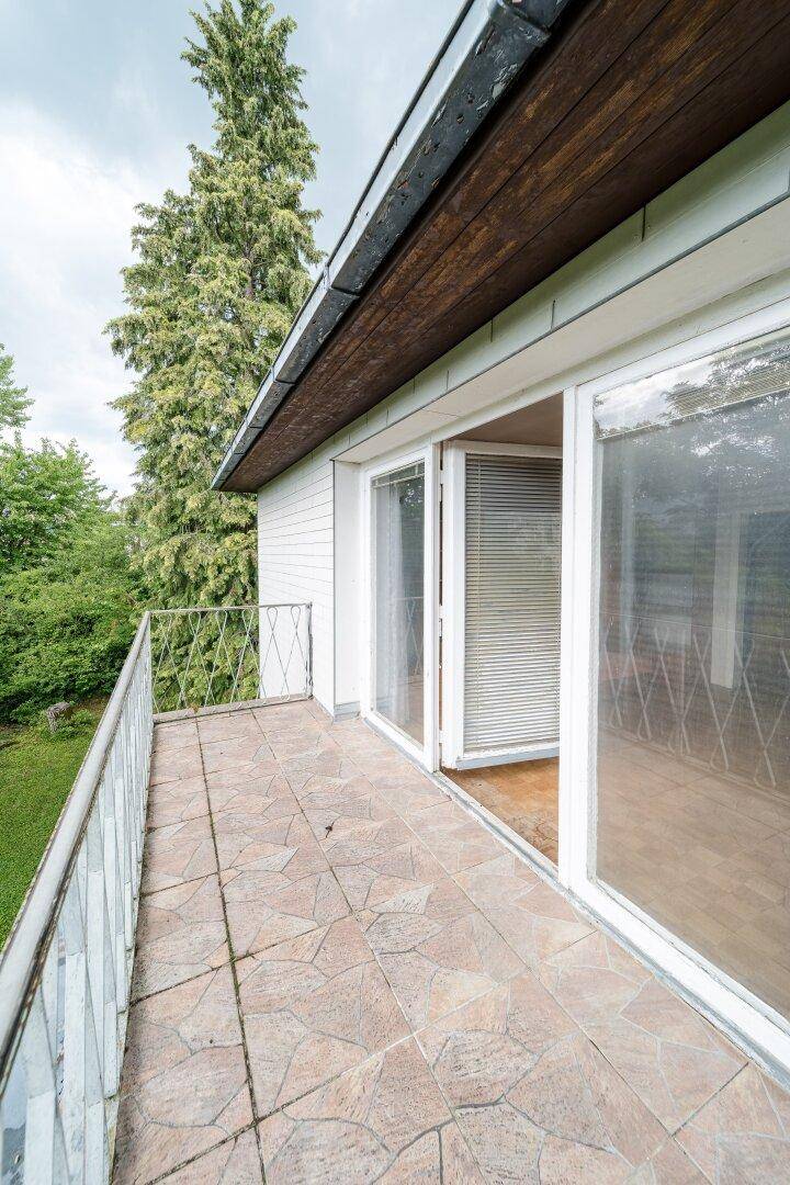 Balkon mit Fliesenboden und Metallgeländer, bietet einen Blick ins Grüne.