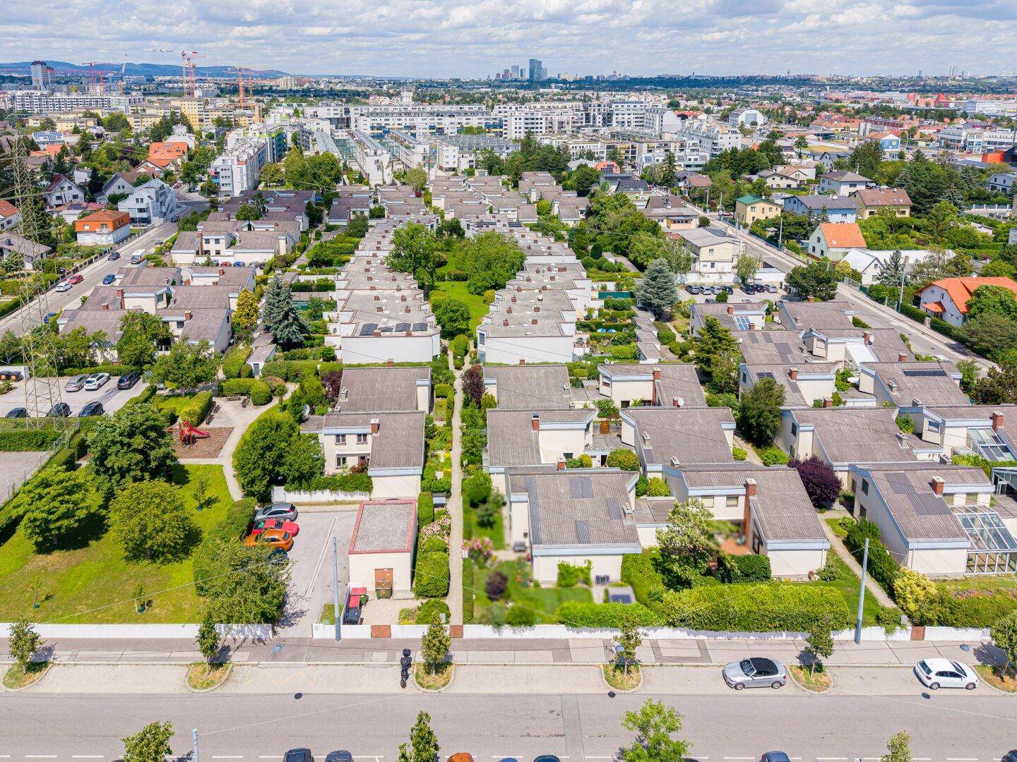 Luftaufnahme einer Wohnsiedlung mit Reihenhäusern und viel Grün in städtischer Umgebung.