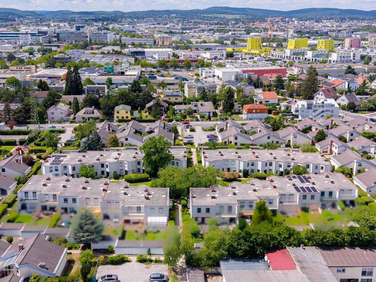 Weitläufige Luftaufnahme einer Wohngegend mit Reihenhäusern und städtischer Infrastruktur.