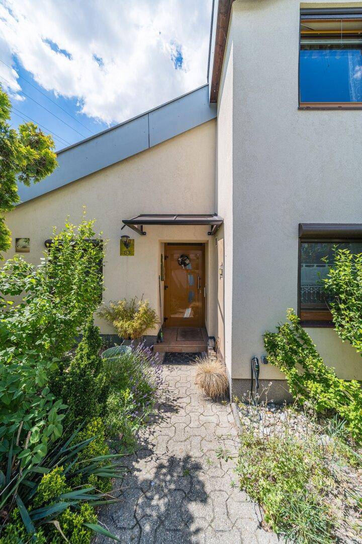Eingangsbereich eines modernen Reihenhauses mit gepflegtem Vorgarten.