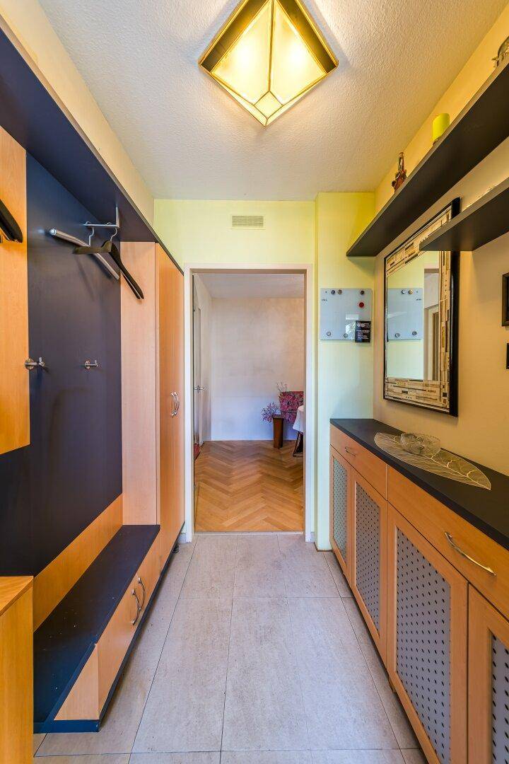 Heller Flur mit Einbauschränken, Garderobe und Fliesenboden.