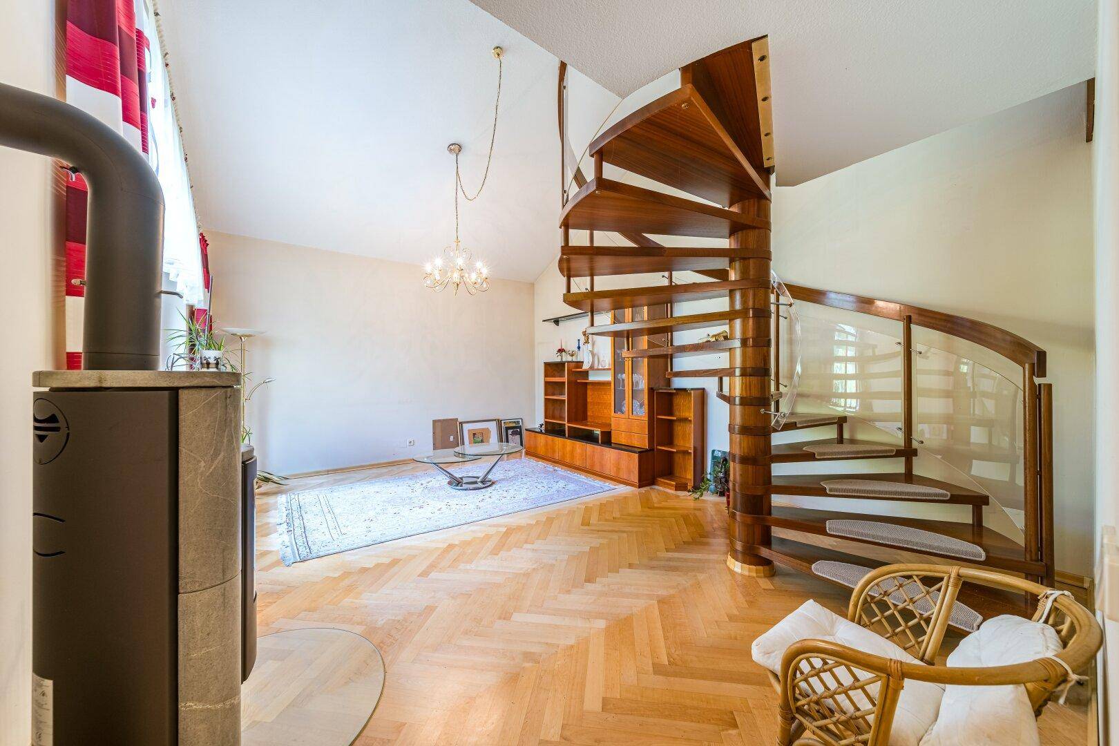 Helles Wohnzimmer mit Fischgrätparkett, Kaminofen und beeindruckender Holzwendeltreppe.