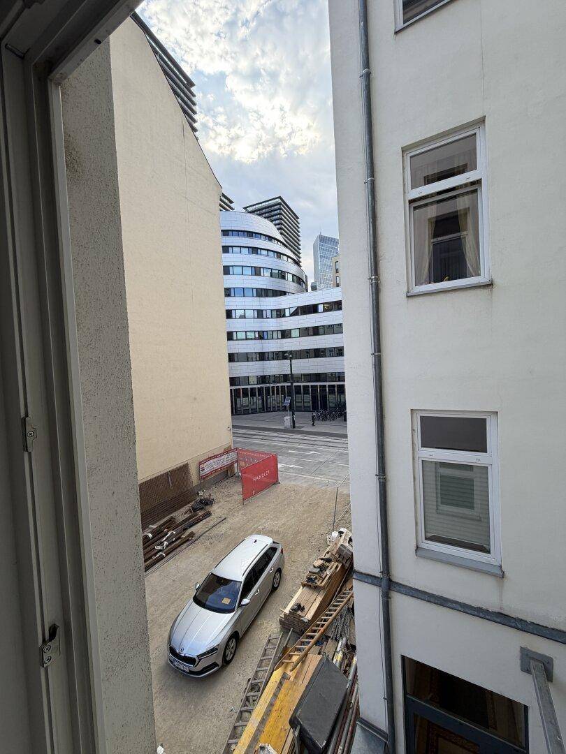 Blick aus einem Fenster auf eine Baustelle und moderne Gebäude in der Ferne.