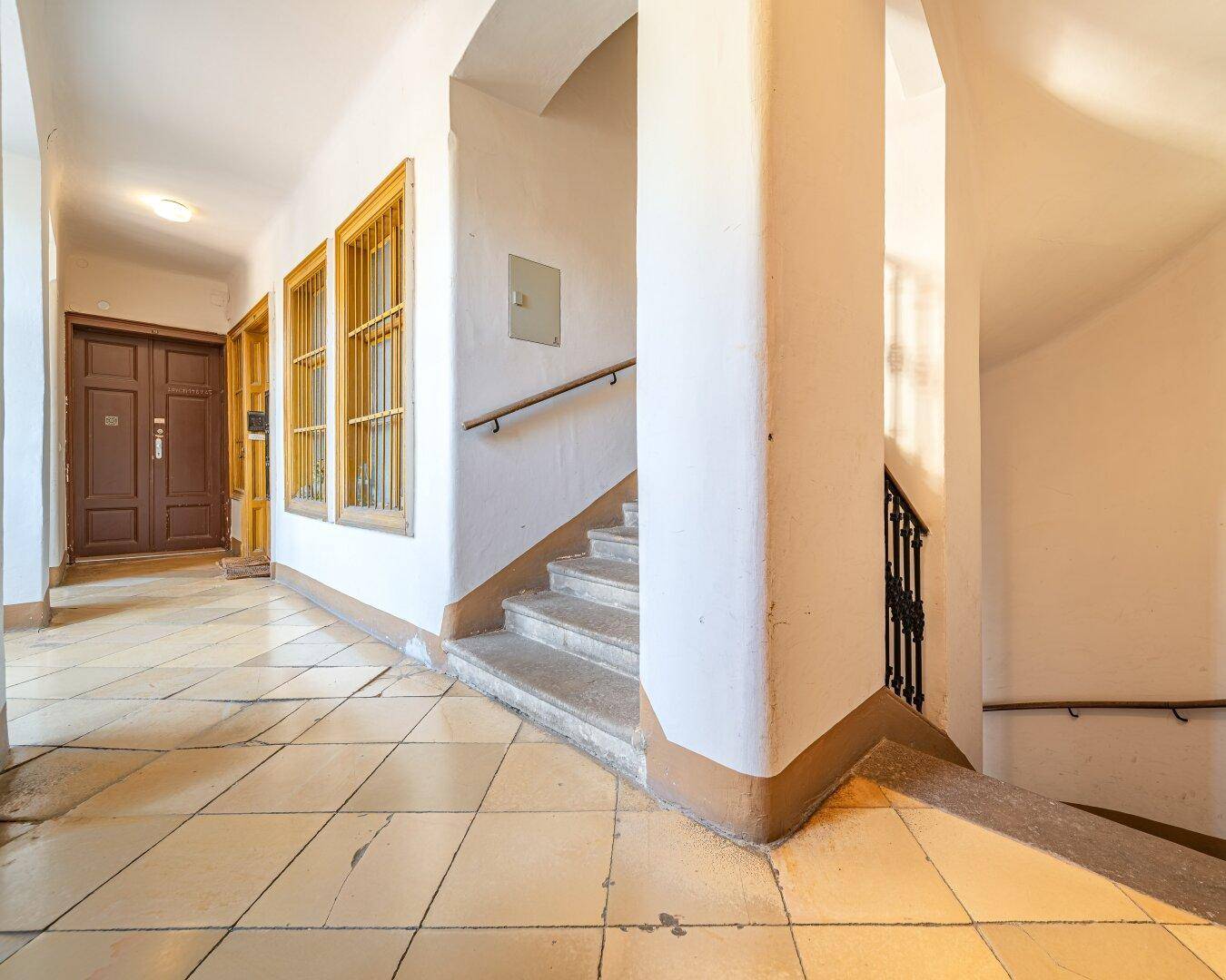 Eingangsbereich mit Treppenaufgang, Fliesenboden und Holzgeländer in einem gepflegten Altbau.