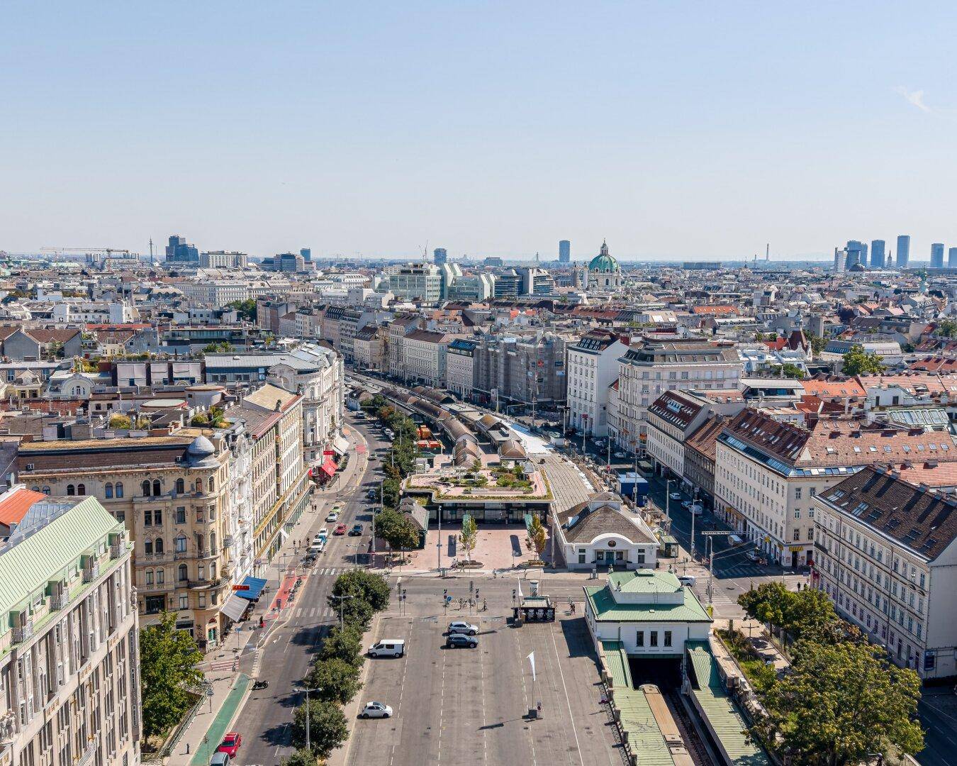 Panoramablick über eine belebte Stadt mit historischen Gebäuden und weitem Horizont unter blauem Himmel.