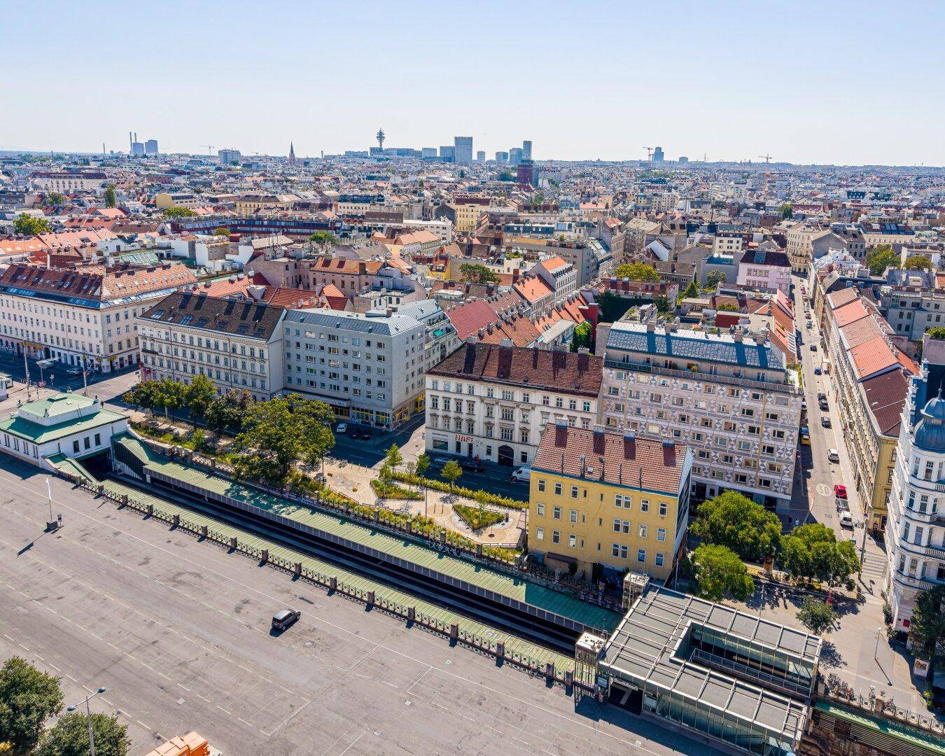 Weitläufiger Luftbildblick auf eine europäische Stadt mit dichter Bebauung und Infrastruktur bei Sonnenschein.