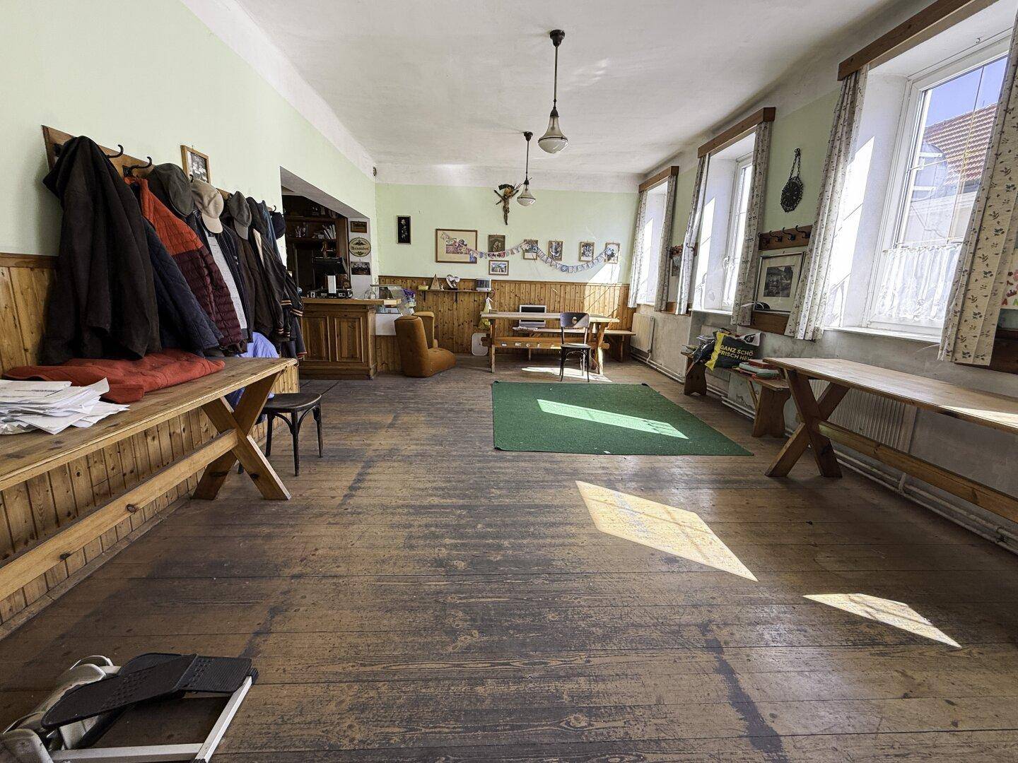 Großer Gemeinschaftsraum mit Holzboden, Garderobe und viel Tageslicht.