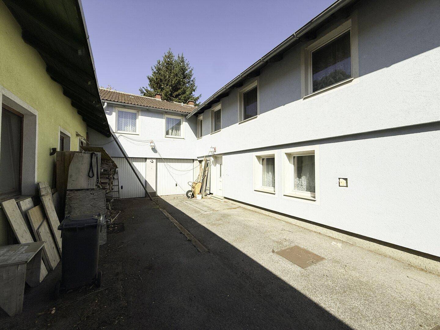 Geräumiger Innenhof zwischen den Gebäuden mit Zufahrt und Garagentoren.
