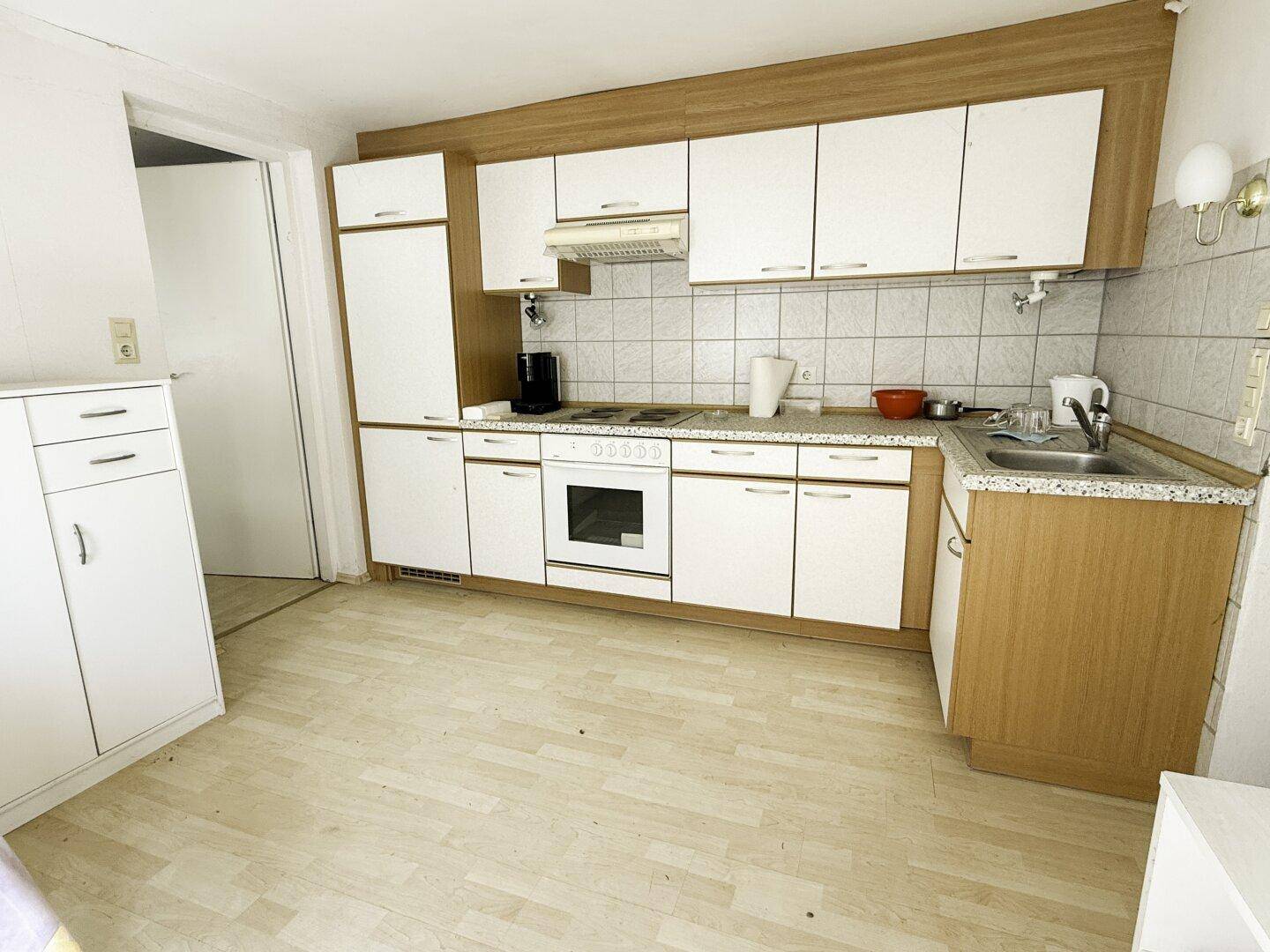 Funktionale Küche mit weißen und holzfarbenen Schränken und Elektrogeräten.
