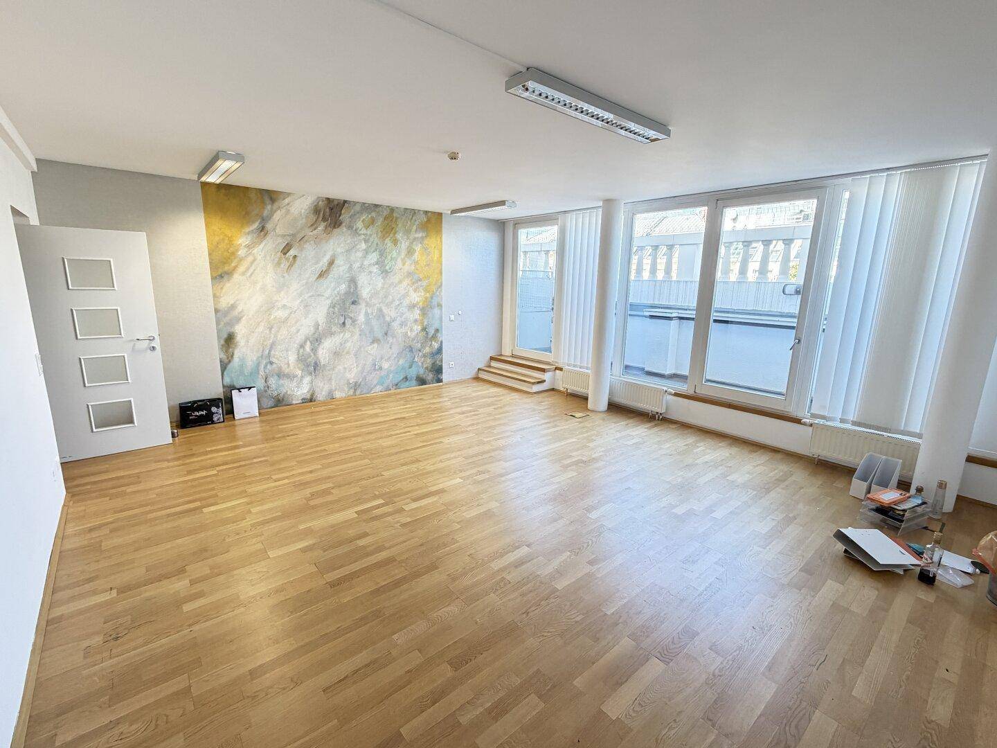 Geräumiger Büroraum mit auffälliger Akzentwand, Holzboden und viel Tageslicht.