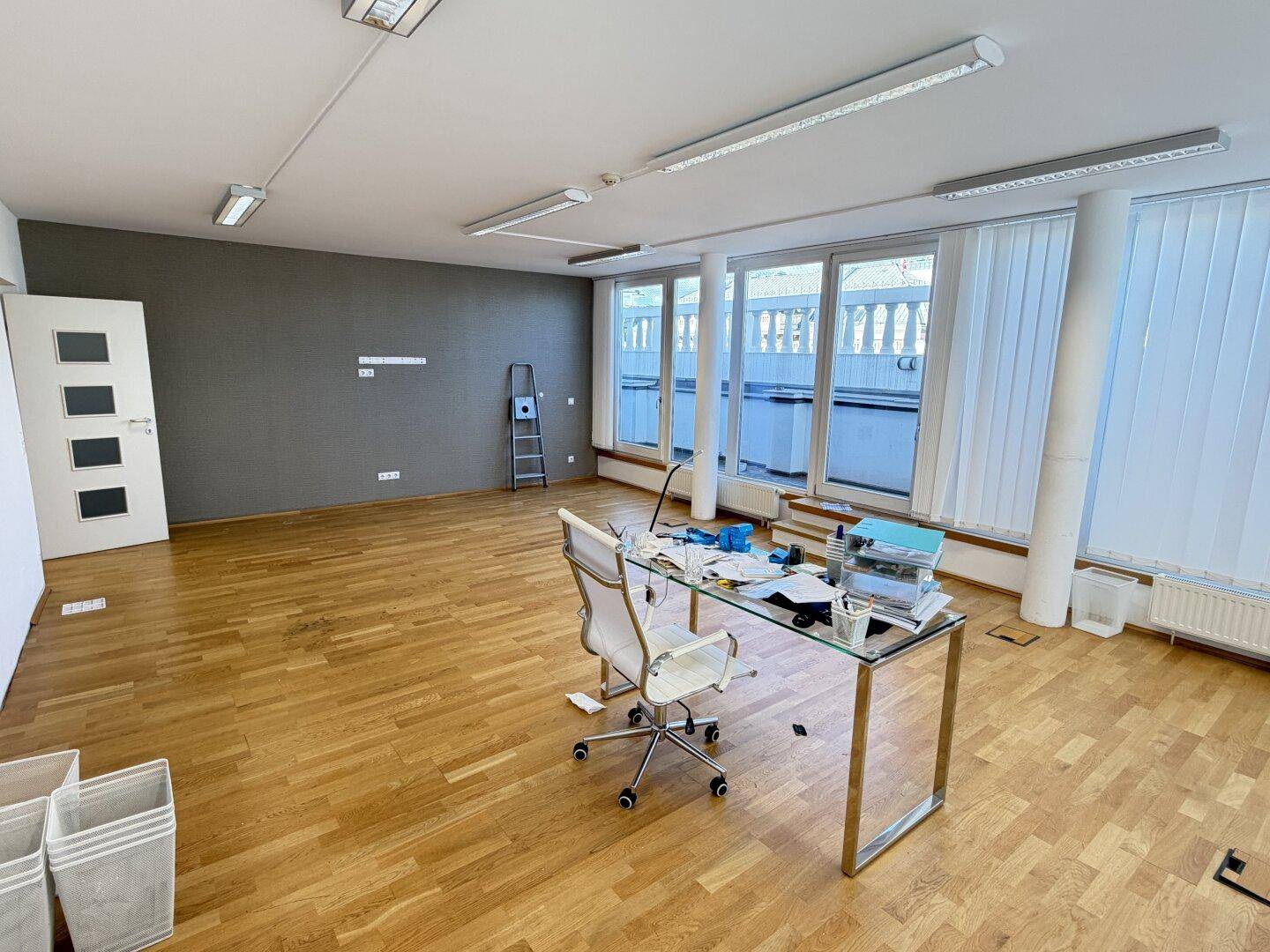 Geräumiges Büro mit Holzboden, grauer Akzentwand und einem modernen Schreibtisch.