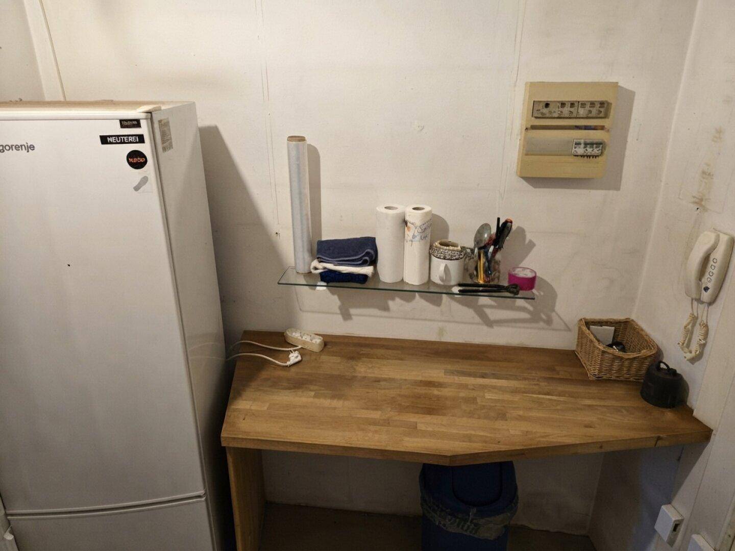 Kleiner Hauswirtschaftsraum mit Kühlschrank, Arbeitsplatte und Sicherungskasten.