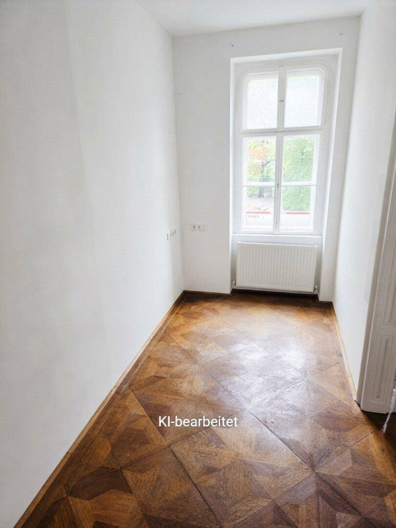 Heller, schmaler Raum mit Parkettboden und großem Fenster, ideal als Schlaf- oder Arbeitszimmer.