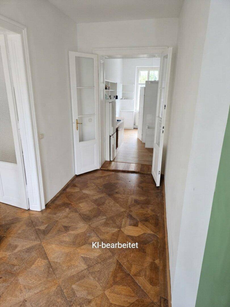 Langer Flur mit Parkettboden, der zu einer Küche mit Fliesenboden und Doppeltüren führt.