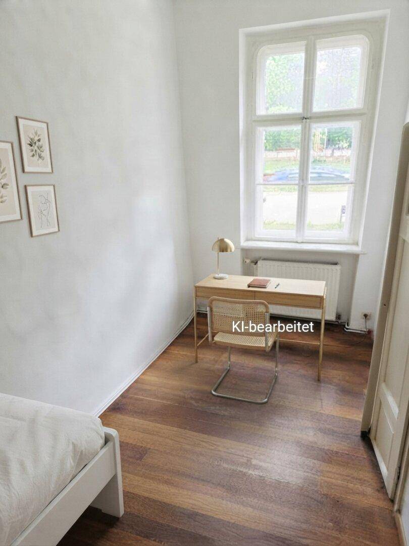 Kleines Arbeitszimmer mit Schreibtisch, Stuhl und dunklem Holzboden.