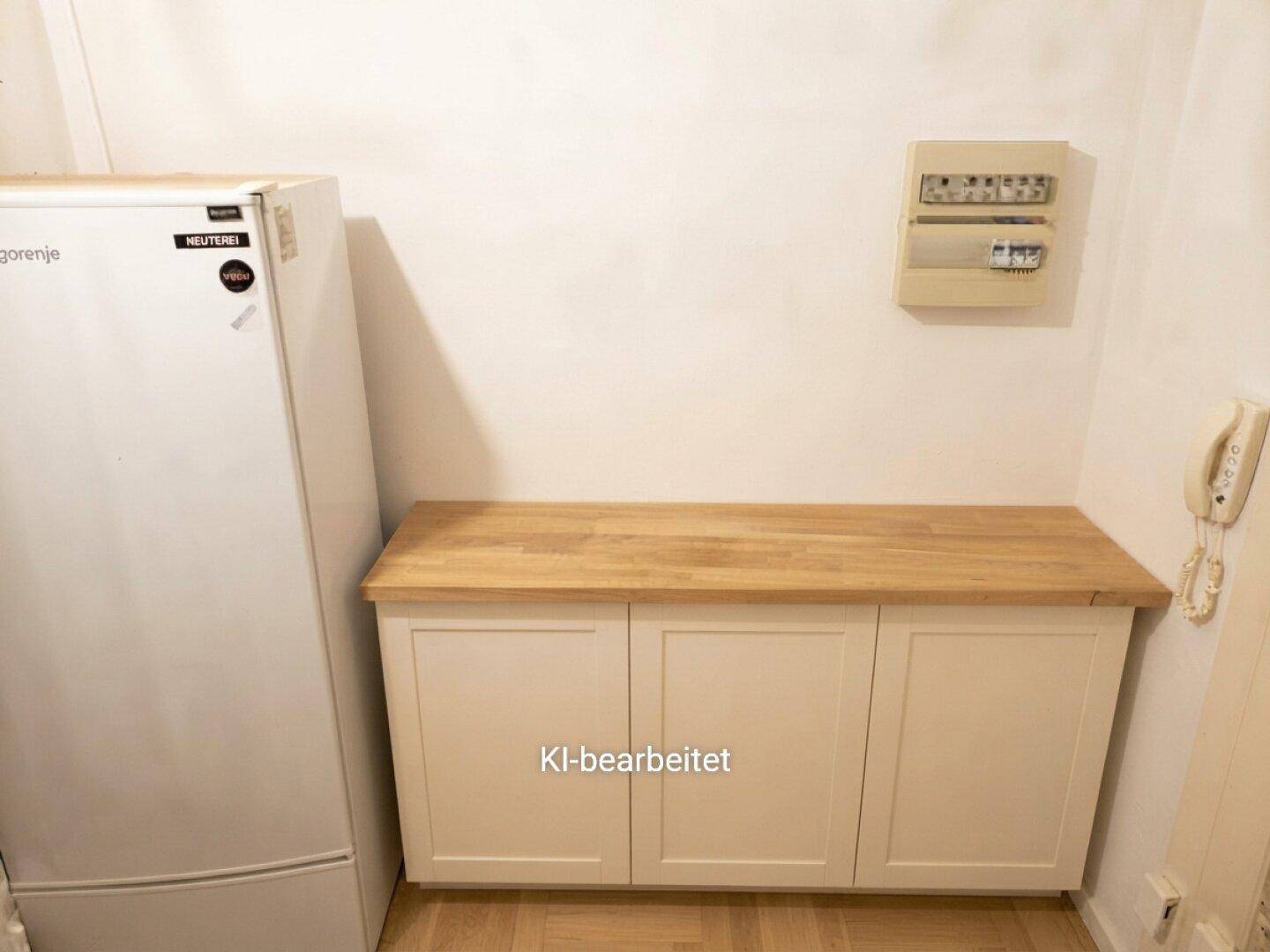 Renovierter Hauswirtschaftsraum mit Kühlschrank, Arbeitsplatte und neuen Unterschränken.