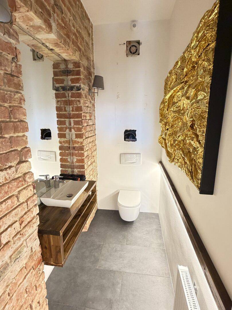 Modernes Gäste-WC mit freiliegender Ziegelwand, Waschtisch und Wand-WC.