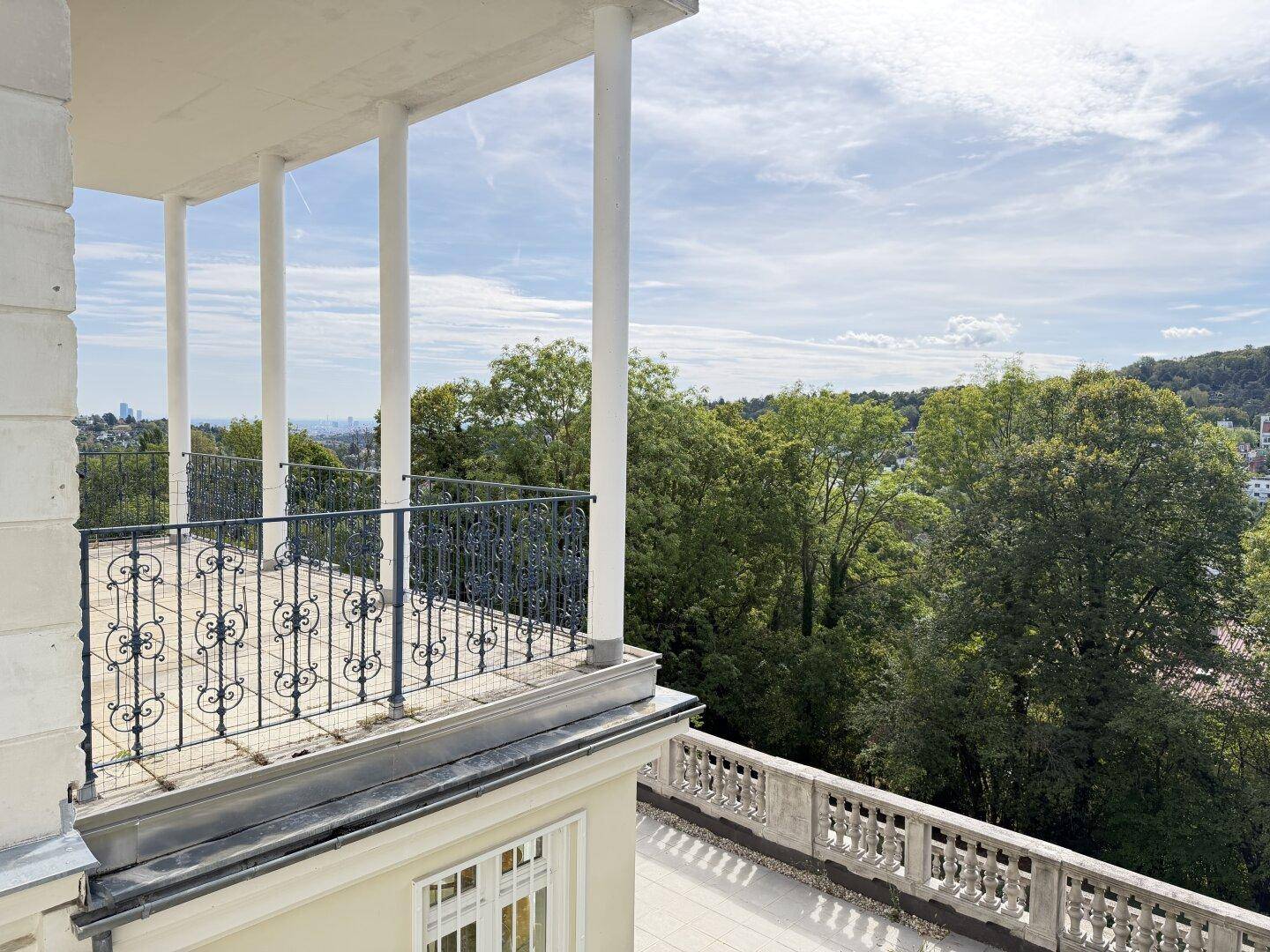 Große Terrasse mit Säulen und schmiedeeisernem Geländer, bietet weite Aussicht.
