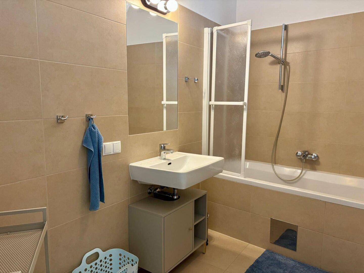 Badezimmer mit Badewanne, Duschabtrennung und Waschbecken mit Spiegelschrank.