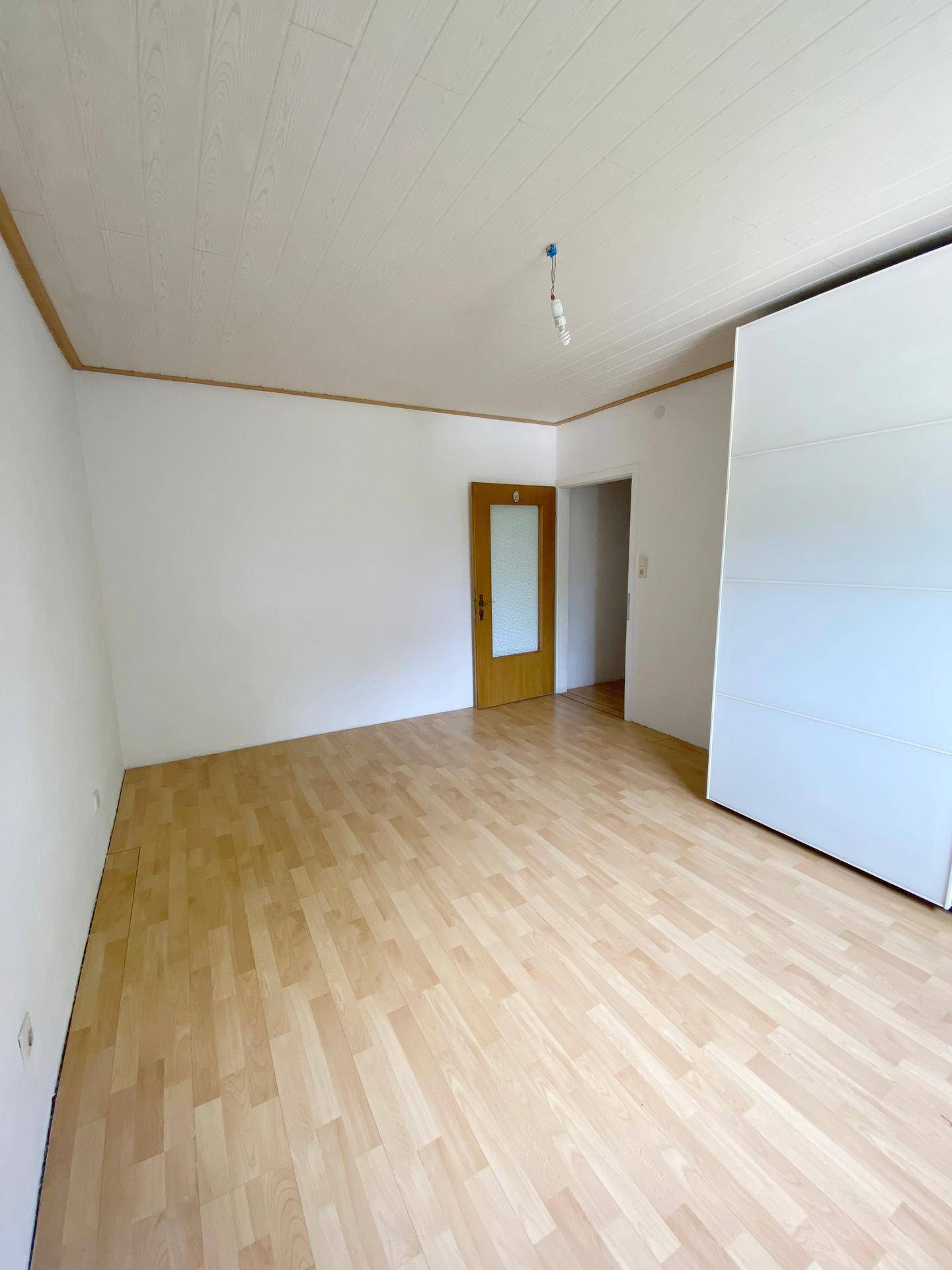 Helles Schlafzimmer mit Laminatboden und weißer Deckenverkleidung, bereit zur individuellen Gestaltung.