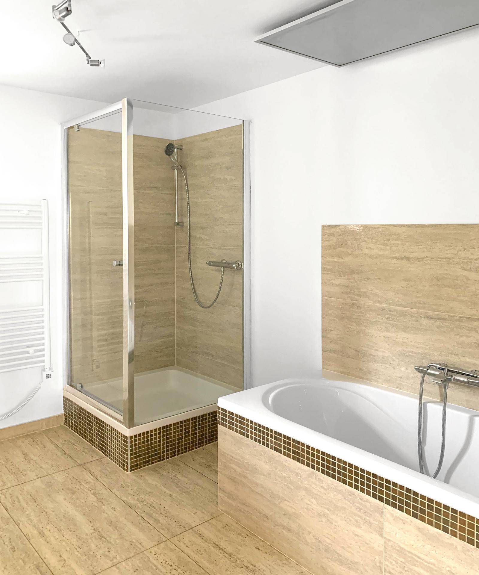 Helles Badezimmer mit Duschkabine, Badewanne und beigefarbenen Fliesen.