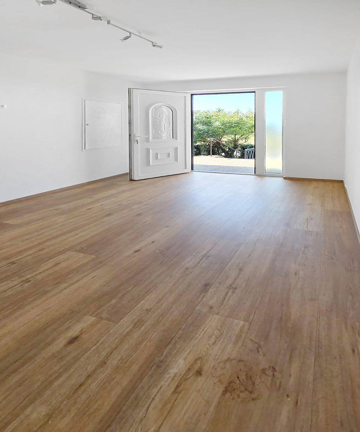 Heller Eingangsbereich mit Holzboden und offener Tür, die viel Tageslicht hereinlässt.
