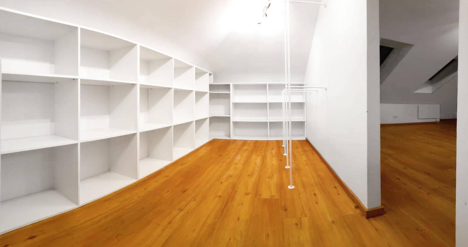 Dachbodenraum mit Holzboden und integrierten Regalen, ideal als Ankleidezimmer oder Lager.