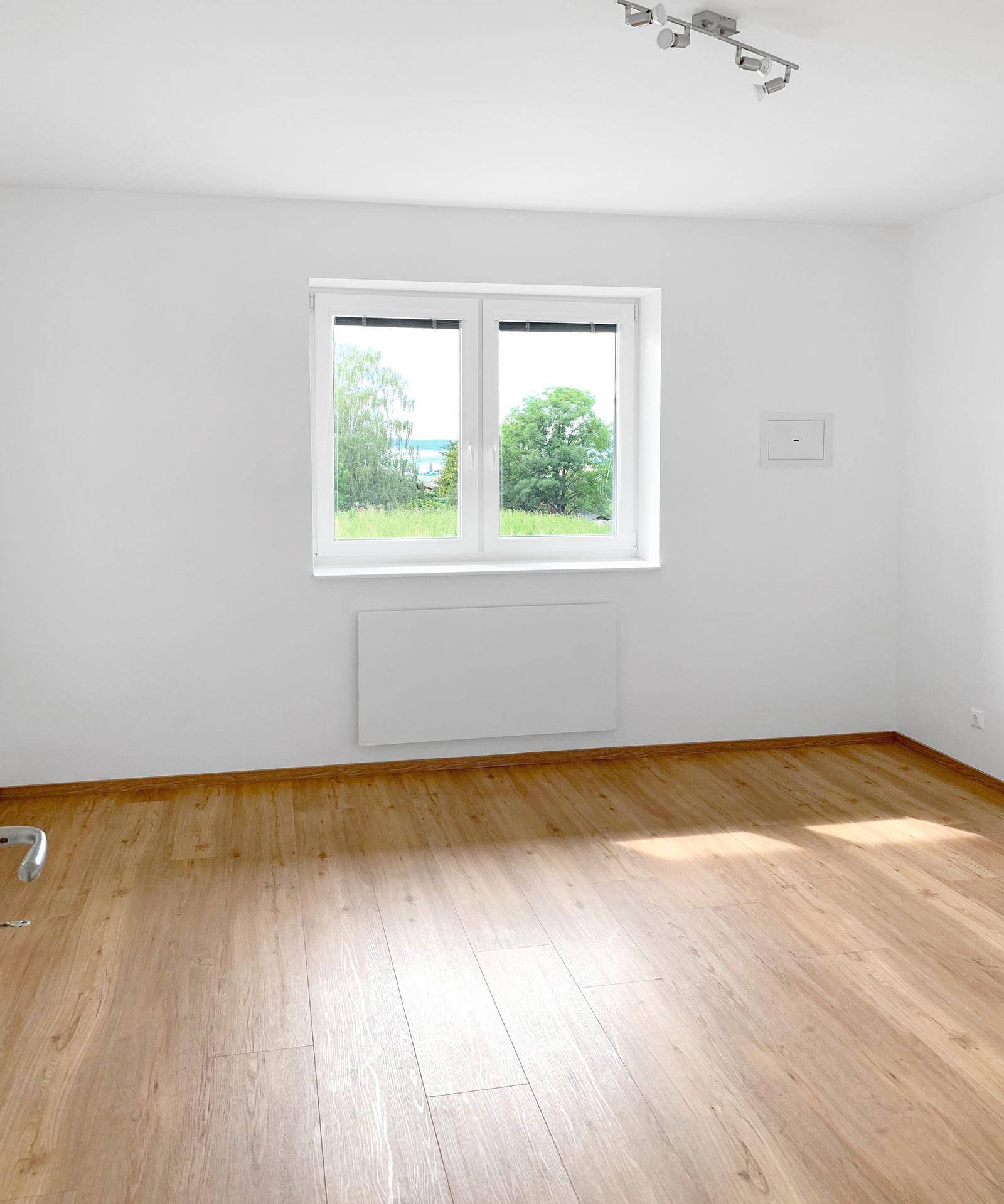 Geräumiges Zimmer mit Holzboden und Fenster, das viel natürliches Licht bietet.