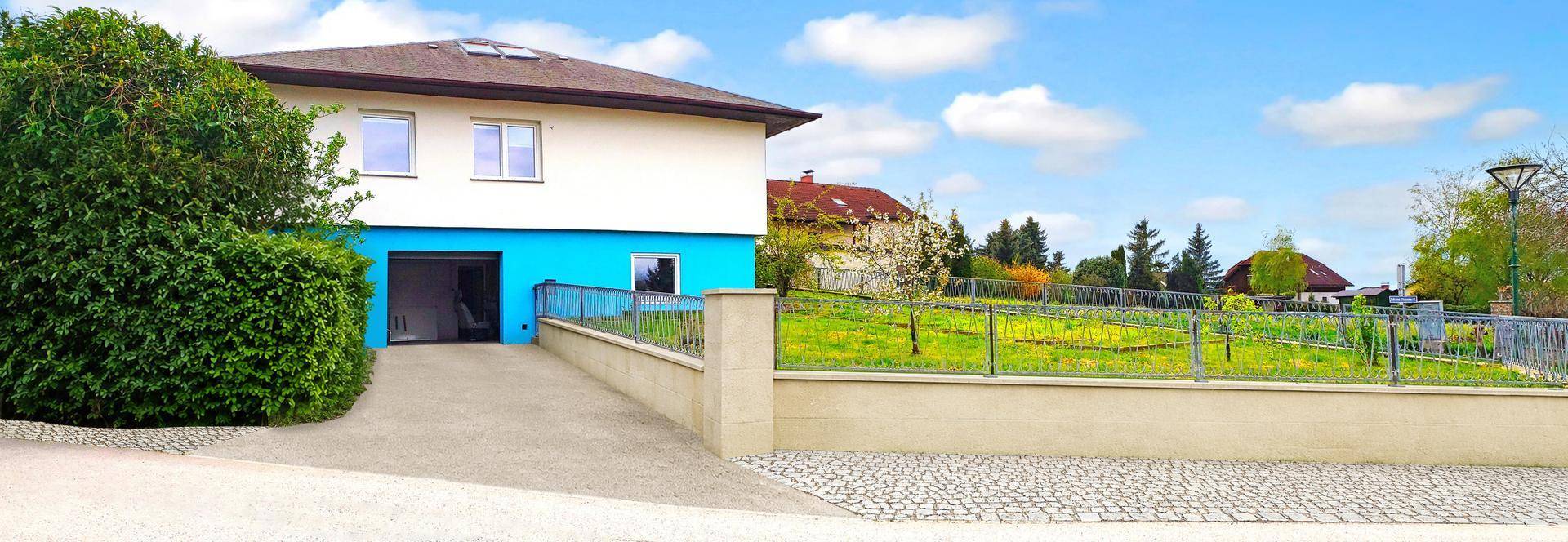 Seitenansicht des Hauses mit Zufahrt zur Garage und weitläufigem Gartenbereich.