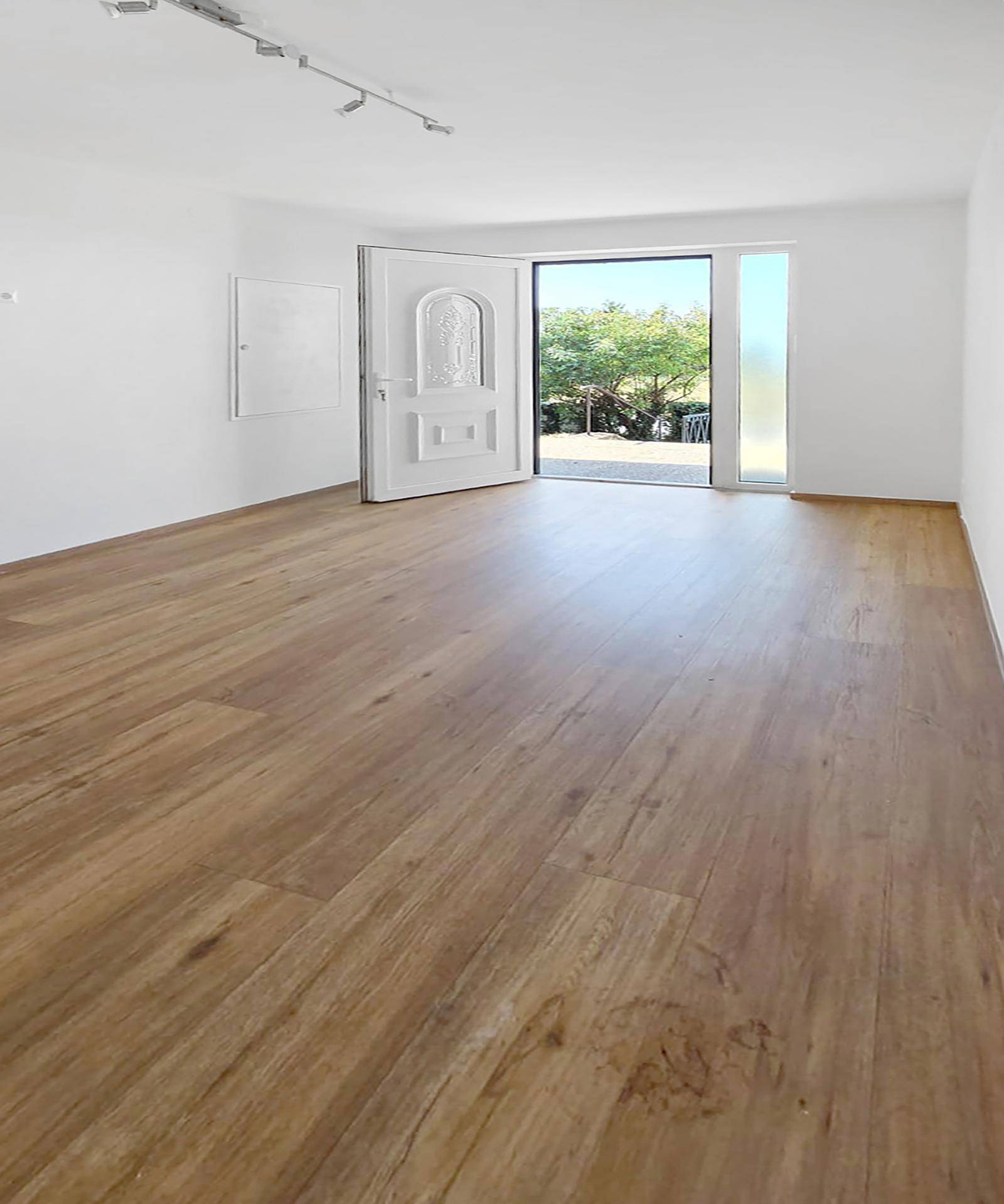 Eingangsbereich mit Holzboden und heller Tür, die viel Tageslicht hereinlässt.